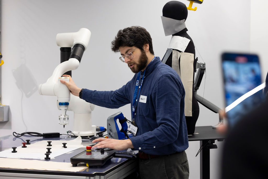 A roboticist guides a collaborative robot in a lab. 